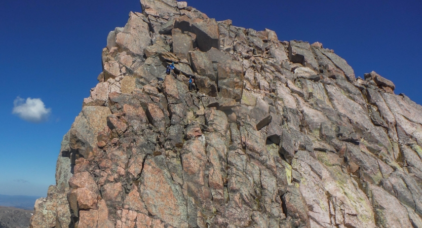 rock climbers make their way up a steep rock wall